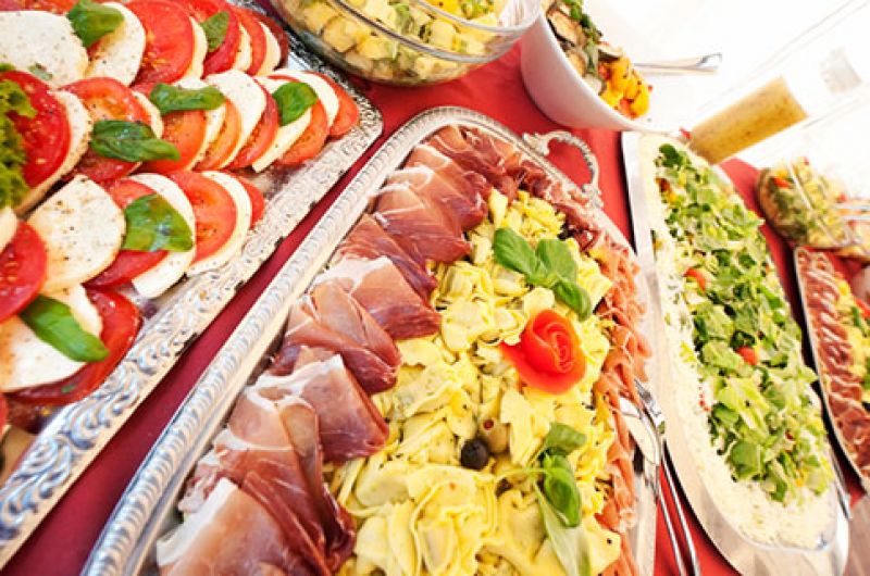 A shared antipasto spread with cured meats and fresh salads